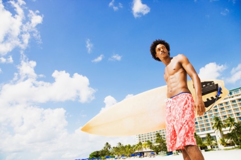 African man holding surfboard on beach