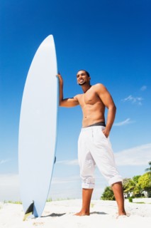 African man holding surfboard on beach