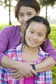 Chinese mother hugging daughter outdoors