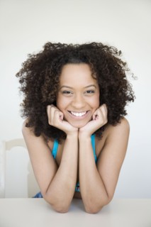 Smiling Hispanic woman with head in hands