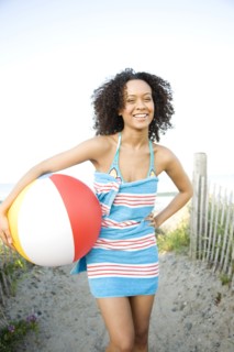 Hispanic woman in towel holding beach ball
