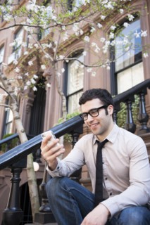 Hispanic businessman using cell phone on front steps