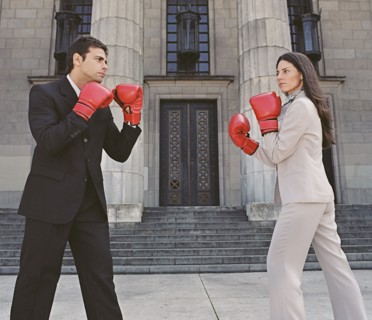 Businessman and businesswoman sparring in front of building