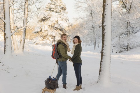 Caucasian couple pulling sled in snow