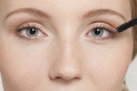 Caucasian woman applying mascara