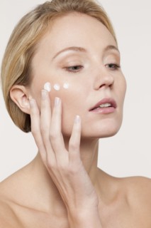 Nude Caucasian woman applying moisturizer