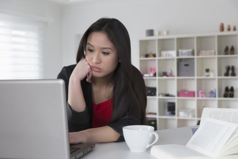 Bored mixed race businesswoman using laptop
