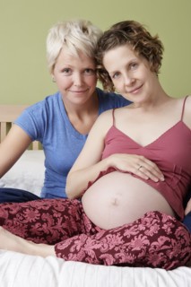 Caucasian pregnant lesbian couple relaxing on bed