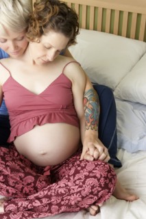 Caucasian pregnant lesbian couple relaxing on bed