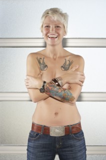 Caucasian woman with bare chest showing off tattoos