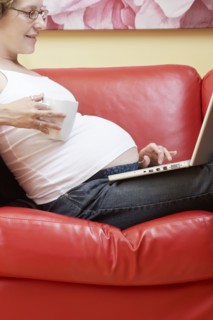 Caucasian pregnant woman using laptop on sofa