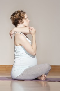 Caucasian pregnant woman stretching on yoga mat