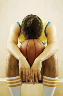 Frustrated Caucasian basketball player sitting on sidelines