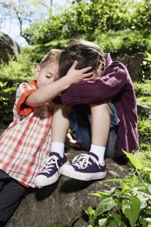 Mixed race boy comforting sister in park