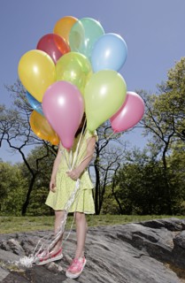 Mixed race girl carrying colorful balloons in park