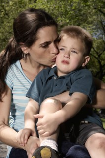 Mixed race mother kissing hurt son in park