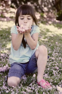 Mixed race girl playing with flowers in park