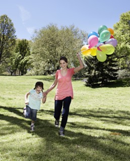 Mixed race mother and daughter holding balloons in park