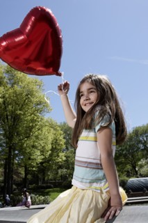 Caucasian girl holding heart-shape balloon