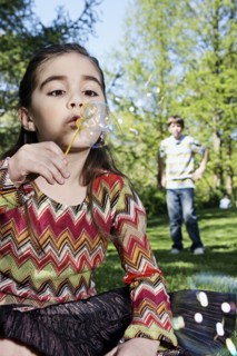 Caucasian girl blowing bubbles in park