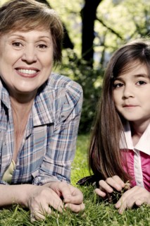 Senior Caucasian woman and granddaughter laying in grass