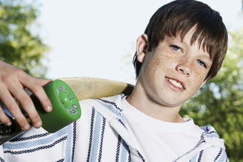 Caucasian boy holding skateboard outdoors