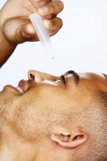 Mixed race man putting in eye drops