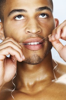 Mixed race man flossing his teeth