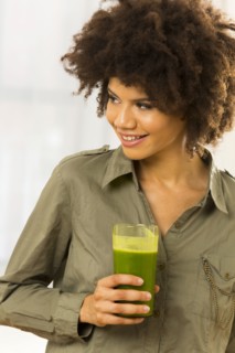 Mixed race woman drinking green smoothie