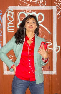 Mixed race woman listening to headphones against graffiti wall