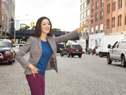 Mixed race woman hailing taxi on city street