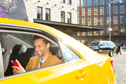 Mixed race businessman using cell phone in taxi