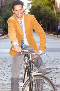 Mixed race businessman riding bicycle on city street