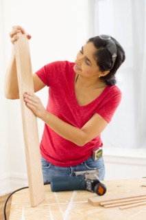 Mixed race woman examining plank of wood