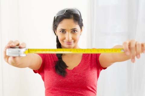 Mixed race woman using measuring tape