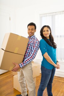 Mixed race couple carrying cardboard boxes in new home