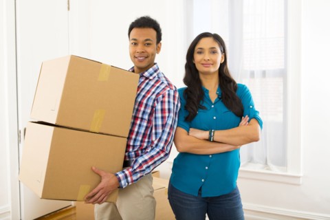 Mixed race couple carrying cardboard boxes in new home