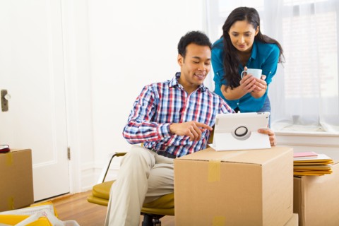 Mixed race couple using digital tablet in new home