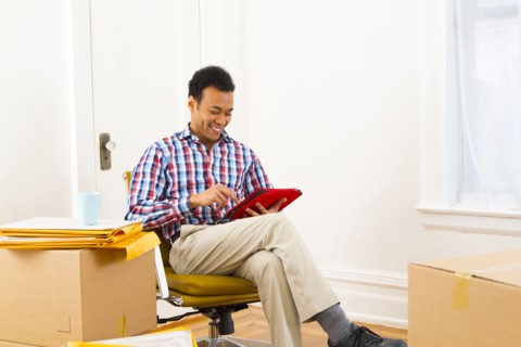 Mixed race man using digital tablet in new home