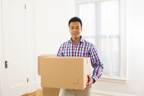 Mixed race man carrying cardboard box in new home