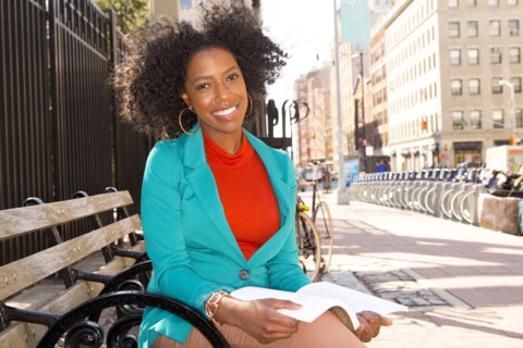 Mixed race woman reading on city bench