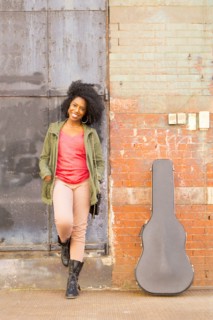 Mixed race woman with guitar case on city sidewalk