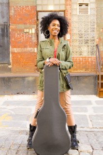 Mixed race woman with guitar case on city street