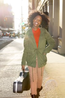Mixed race woman carrying guitar case on city sidewalk