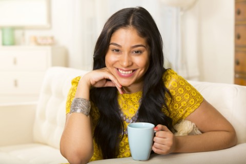 Hispanic woman having cup of coffee