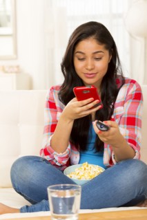Hispanic woman using cell phone on sofa