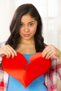 Hispanic woman holding broken heart
