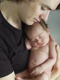 Father cuddling newborn baby