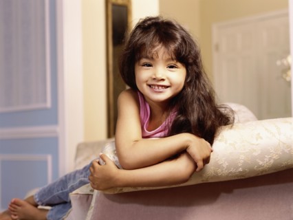 Mixed race girl leaning over edge of sofa