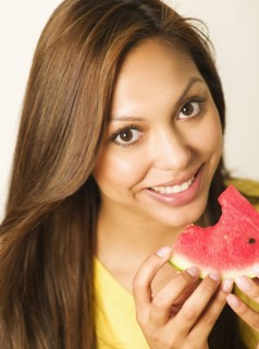 Close up of smiling Hispanic woman eating watermelon